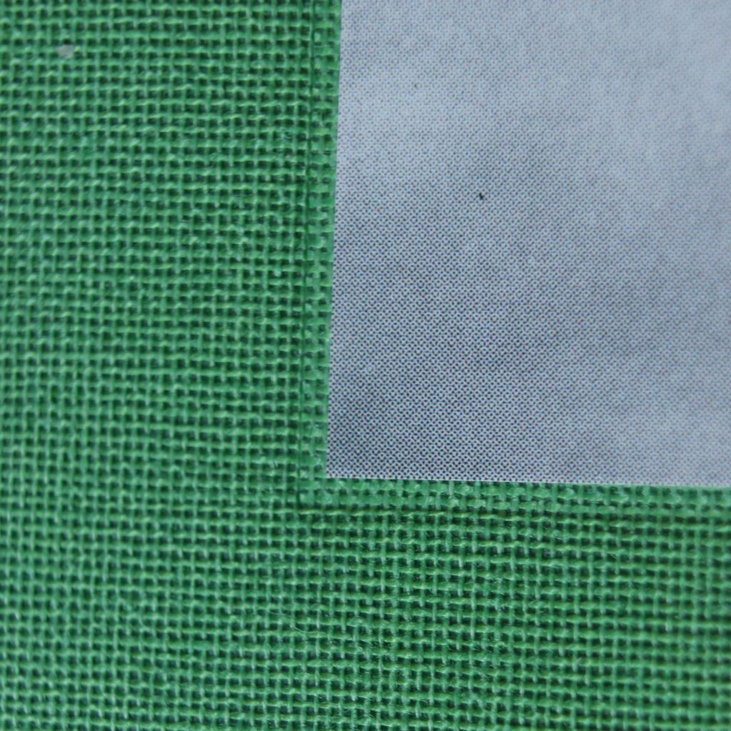 Very close-up detail of a green cloth-bound book.